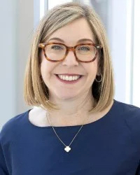 Portrait of a smiling woman with glasses, likely a researcher or healthcare professional.